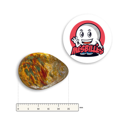 Bille Oeuf Ambre Moucheté Vert et Orange couchée à côté d'une règle graduée, environ 25 mm de long