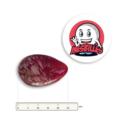 Bille Oeuf Rouge Moucheté Blanc couchée à côté d'une règle graduée, environ 25 mm de long